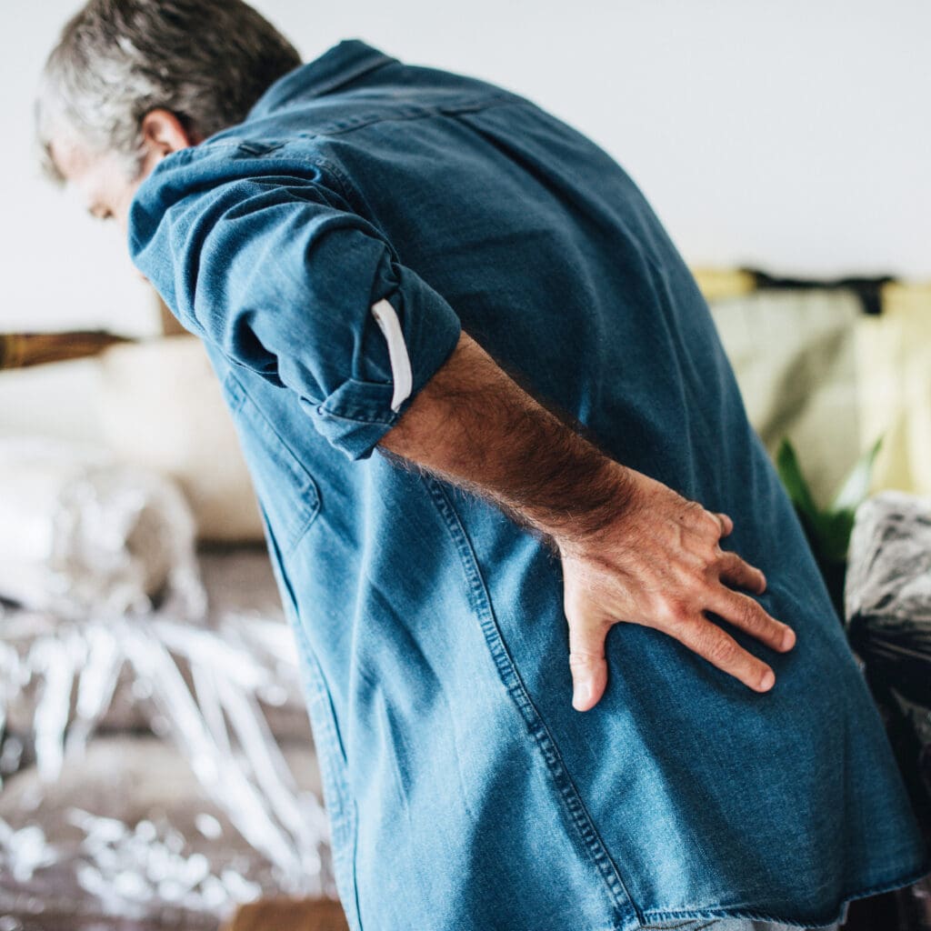 man leaning on bed because of back pain